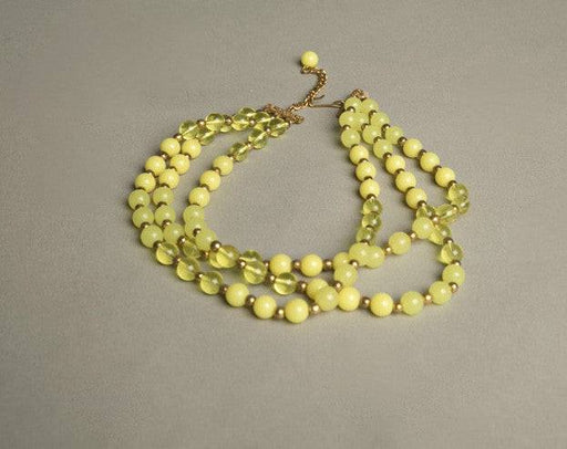 Yellow plastic necklace with three strands of beads in varying yellow shades and golden spacers, vintage 1960s.