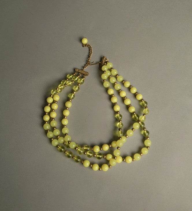 Yellow plastic necklace with three strands of beaded vintage jewelry with golden spacers.