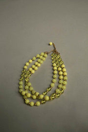 Yellow plastic necklace with three strands of vintage beads and golden spacers, 1960s.