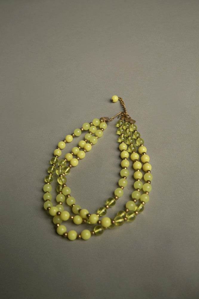 Yellow plastic necklace with three strands of vintage beads and golden spacers, 1960s.