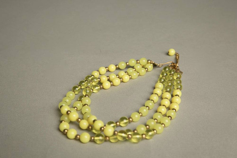 Yellow plastic necklace with three strands of vintage beaded jewelry in various yellow shades and golden spacers.
