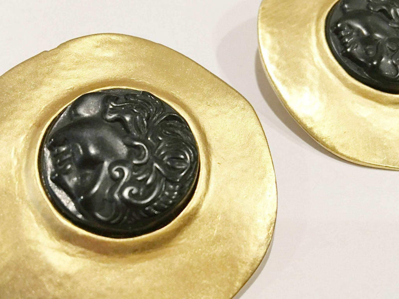 Merlusa Hercules Clip on Earrings featuring golden modernist frames and textured Greek face design.