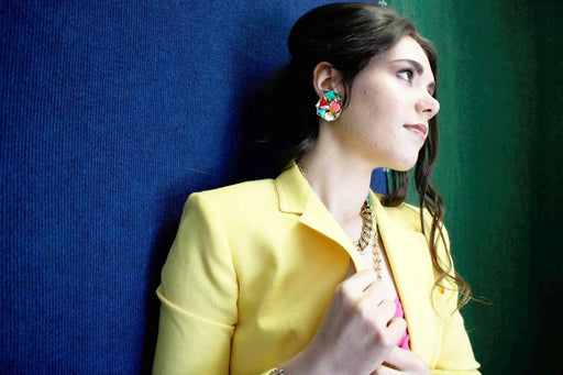 Handmade vintage clip on earrings with colorful design worn by a woman in a yellow jacket.