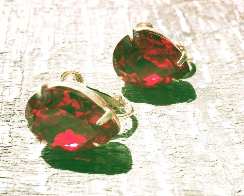 Miriam Haskell vintage red rhinestone earrings on textured surface.