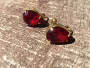 Miriam Haskell vintage earrings with red rhinestones and golden findings on wood background.