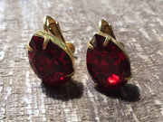 Miriam Haskell vintage red rhinestone earrings on wooden surface, featuring deep red stones set in golden findings.