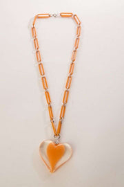 Vintage plastic jewelry necklace with chain links and a large clear heart pendant, 1960s design.