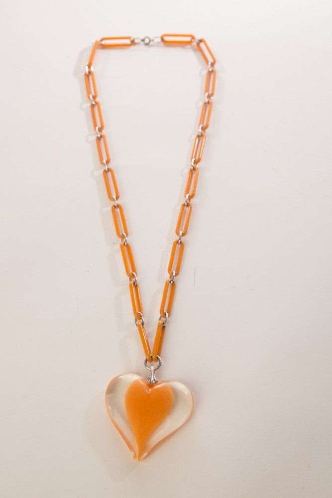 Vintage plastic jewelry necklace with chain links and a large clear heart pendant, 1960s design.